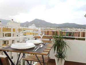 una mesa con platos y copas de vino en el balcón en Aries Flat, en Benalmádena