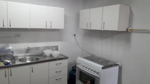 uma cozinha com armários brancos, um lavatório e um fogão em Casa para 12 pessoas em Piratuba