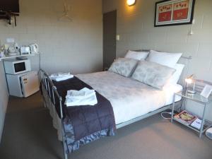 a bedroom with a bed with a table and a microwave at Waitomo Golfstays B&B in Otorohanga