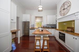 a kitchen with white cabinets and a wooden table and stools at Barossa Valley View Guesthouse in Tanunda