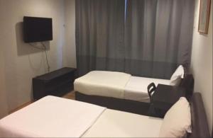 a small room with two beds and a tv at Hotel Conforto in Singapore