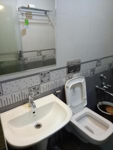 a bathroom with a sink and a toilet and a mirror at Suroor Tourist Home in Virajpet