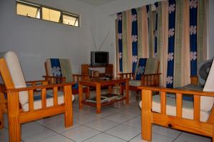 a living room with wooden chairs and a tv at Villas Pingouin in Blue Bay