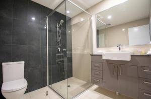 a bathroom with a shower and a toilet and a sink at Magnum Serviced Apartments in Darwin