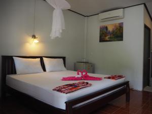 a bed with white sheets and a pink ribbon on it at Bluesky Beach Bungalows in Ko Lanta
