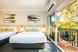 a bedroom with a bed and a balcony at Nightcap at Blue Cattle Dog Hotel in Rooty Hill