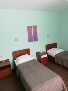 クルガンにあるHotel Kniiekotのベッド2台が備わる客室で、壁には絵画が飾られています。