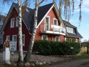 a house with a red house with a balcony at Ferienwohnung Fischerkoje in Wustrow