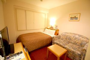 Smile Hotel Tokyo Shinkoiwa في طوكيو: غرفه فندقيه بسرير واريكه