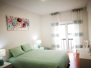 a bedroom with a green bed and a window at Peniche's Blue & White in Peniche