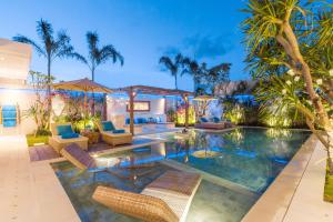 an indoor pool with chairs and palm trees at Villa Smilla in Seminyak
