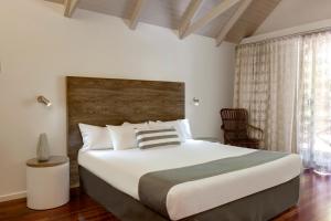a bedroom with a large bed with a wooden headboard at Palm Bungalows in Hamilton Island