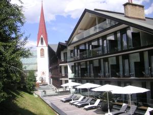 budynek z krzesłami i parasolami oraz kościół w obiekcie Alpenlove - Adult SPA Hotel w mieście Seefeld in Tirol