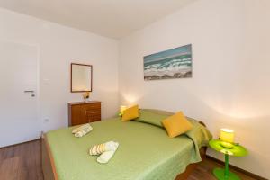 ein kleines Schlafzimmer mit einem grünen Bett und gelben Kissen in der Unterkunft Apartments Petra in Bol
