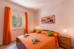 Schlafzimmer mit einem Bett mit orangefarbener Bettwäsche und grünen Kissen in der Unterkunft Apartments Petra in Bol