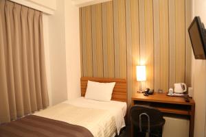 a hotel room with a bed and a desk and a television at Tokyo Ueno New Izu Hotel in Tokyo