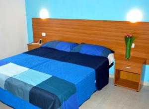 a bedroom with a blue bed with a wooden headboard at Tindari Village Camping in Furnari +25 photos