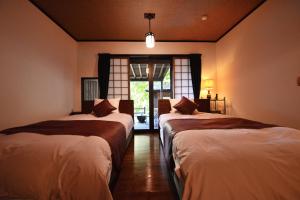 two beds in a room with a window at Sanso Tensui in Hita