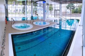 a swimming pool with three sinks in a building at Koral Live in Kołobrzeg