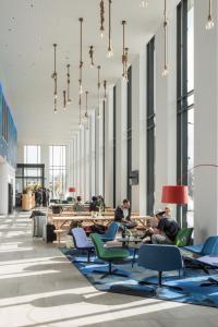 a group of people sitting at tables in a lobby at MEININGER Hotel Amsterdam Amstel in Amsterdam