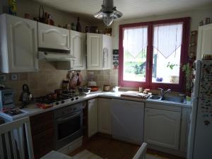 a kitchen with white cabinets and a sink and a window at Le clos in Lugrin