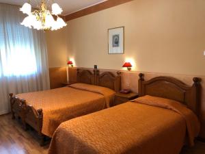two beds in a hotel room with a chandelier at Hotel Victoria in Bassano del Grappa