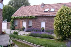 a brick house with purple flowers in front of it at B&B De Pepelinck in Denderwindeke