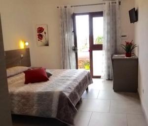 - une chambre avec un lit doté d'un oreiller rouge dans l'établissement B&B Campu Moru, à Bari Sardo