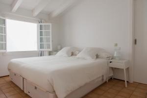 Un dormitorio blanco con una gran cama blanca y una ventana en Squella, en Ciutadella