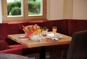 una mesa con una cesta de pan y vasos de zumo de naranja en Landgasthof Karolinenhöhe, en Lichtenfels