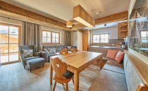 a kitchen and living room with a wooden table at Chalet Guter Hirte in Saalbach Hinterglemm