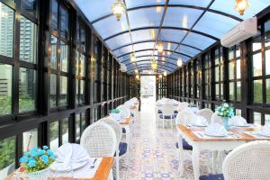 d'une salle à manger avec des tables, des chaises blanches et des fenêtres. dans l'établissement M Home, à Jakarta