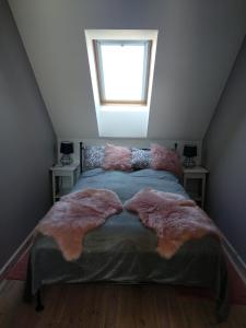 a bedroom with a bed with furry pillows and a window at Apartament in Olsztyn