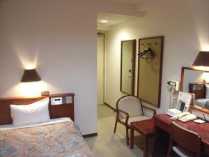 a hotel room with a bed and a desk and a mirror at Smile Hotel Koriyama in Koriyama