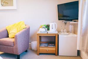 Una sala de estar con una silla y un televisor. en Ferlas Bed and Breakfast, en Penrhyndeudreath