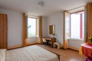 a bedroom with two beds and a desk and windows at Al Villino Sunshine appartamento in villa con piscina in SantʼAlfio +27 photos