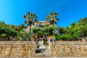 a house with palm trees behind a stone wall at Two Palms Villa in Zaton
