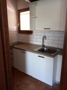 a kitchen with white cabinets and a sink and a window at Agriturismo Costiolu in Nuoro