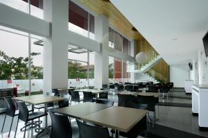 un comedor con mesas, sillas y ventanas en Amaris Hotel Tendean, en Yakarta