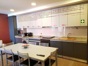 eine Küche mit Tisch, Spüle und Arbeitsfläche in der Unterkunft Junqueira76 Guesthouse in Póvoa de Varzim
