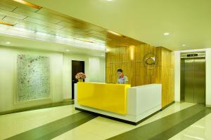 a woman standing behind a yellow counter in a lobby at Amaris Hotel Tendean in Jakarta