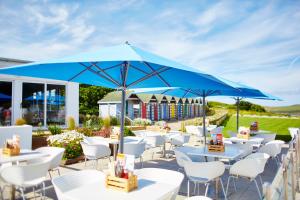 a group of tables and chairs under a blue umbrella at St Moritz Hotel and Cowshed Spa in Polzeath