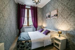 ズビエジニエツにあるApartamenty Roztoczeの紫色のカーテンとベッド、窓が備わるベッドルーム1室が備わります。
