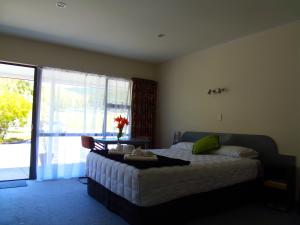 a bedroom with a bed and a large window at Kapiti Lindale Motel and Conference Centre in Paraparaumu