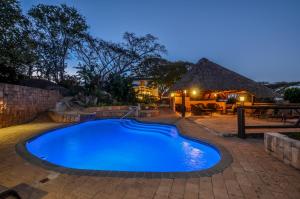a swimming pool in a yard with a thatch roof at White House Lodge in White River