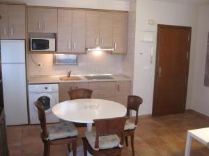 una pequeña cocina con mesa blanca y sillas en acogedor y céntrico apartamento, en Alicante