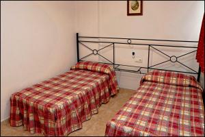 1 dormitorio con 2 camas y manta a cuadros en Apartamento Sol II, en Conil de la Frontera