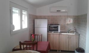 a small kitchen with a white refrigerator and a table at Danijela Apartmani in Čanj