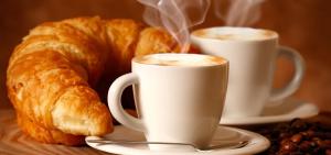 two cups of coffee and croissants on a table at Gli Agrumi Rooms in Trapani