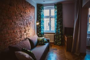 - un salon avec un canapé et un mur en briques dans l'établissement Apartament Koci Łeb, à Toruń